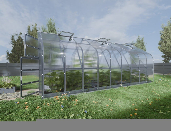 Glass greenhouse on a grassy area with trees in the background