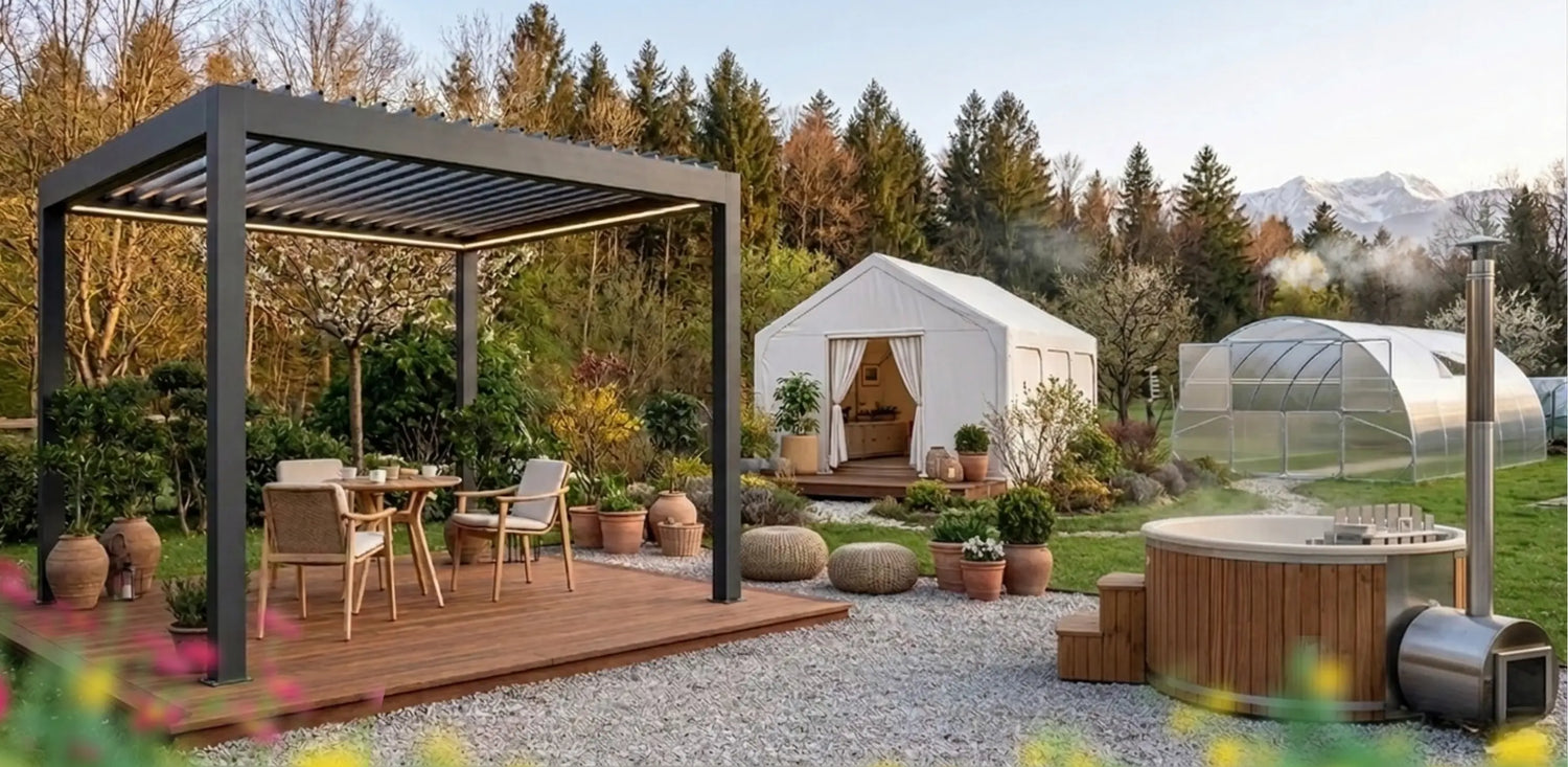Modern luxury garden at golden hour with a black pergola on a wooden deck, a wood-fired hot tub with the heater and chimney placed on the right side, a white glamping tent, and an arched polycarbonate greenhouse showing rows of young plants starting to grow inside, set against trees and distant snowy mountains.