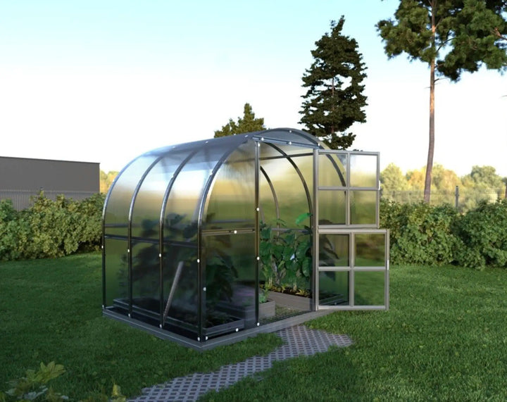 Polycarbonate greenhouse on a grassy area with trees in the background