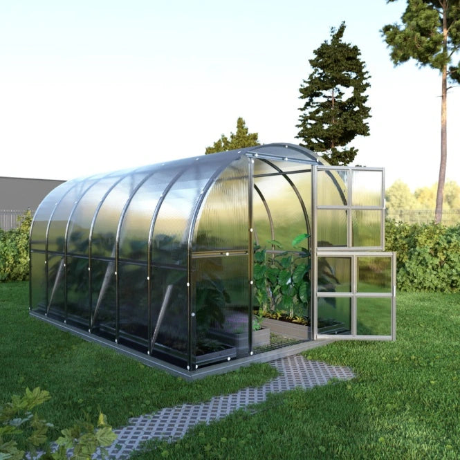 Glass greenhouse with transparent walls on a grassy area with trees in the background