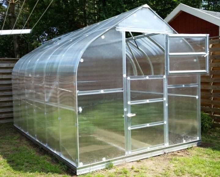 Polycarbonate greenhouse with metal frame on a grassy area