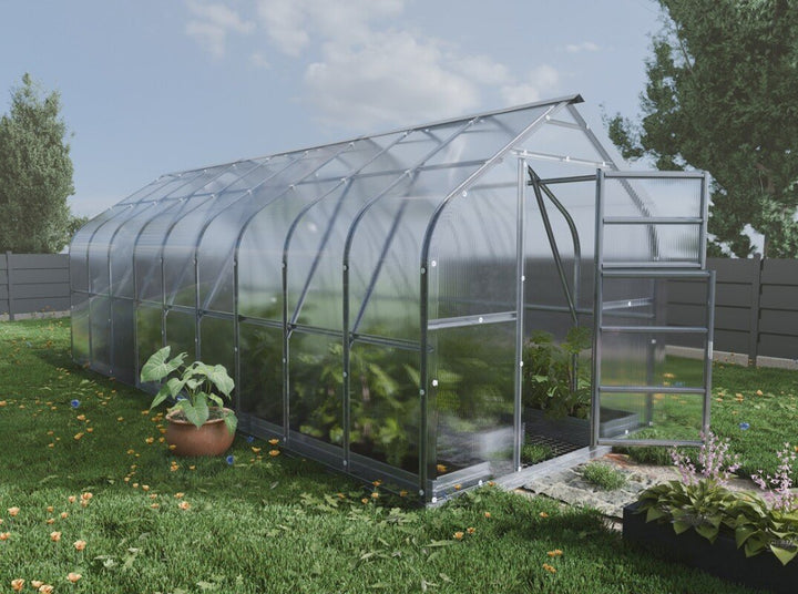 Greenhouse with plants on a grassy area under a clear sky