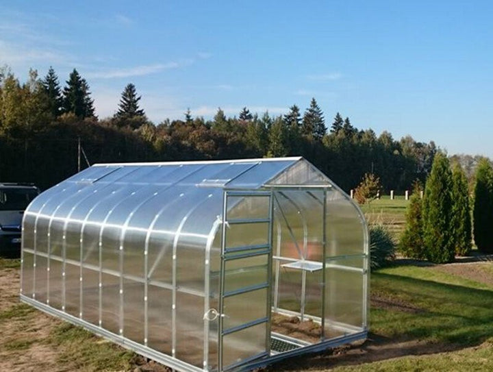 Greenhouse in a garden with trees and clear sky